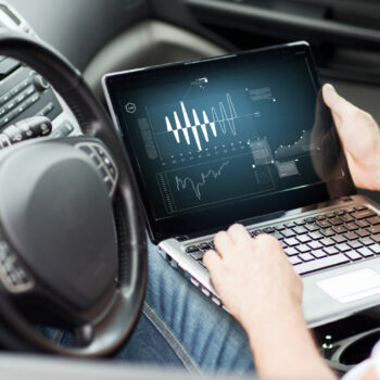 transportation and vehicle concept - man using laptop computer in car